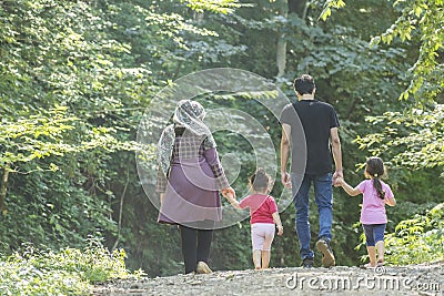 Backside of young family walking together outside in green nature Stock Photo