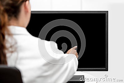 Backview, female doctor is pointing on a black desk or monitor w Stock Photo