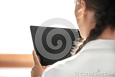 Backview of a young woman, tablet with copyspace in her hands Stock Photo