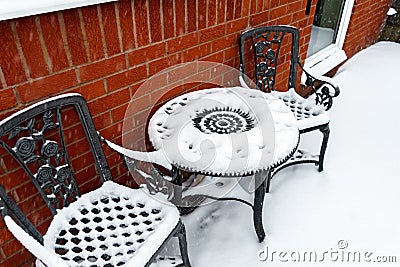 Backyard outdoor table and chairs on a patio covered with a thick layer of snow after snowfall in Devon, England Stock Photo