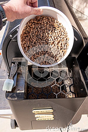 Backyard smoker with hopper open and getting read to add pellets Stock Photo