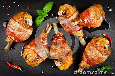 Bacon wrapped chicken legs on a black background Stock Photo