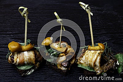 Bacon wrapped with agaric mushrooms on wooden table, appetizer Stock Photo