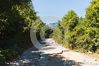 Bad broken road to the mountains. Serpentine to the mountains Stock Photo