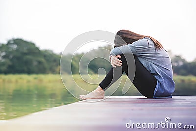 Bad Day Concept. Sadness Woman Sitting by the River on Wooden Patio Deck Stock Photo