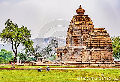 Two women care for grass in front of a Bhuthnath temple carved with intricate Hindi gods Editorial Stock Photo