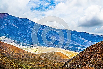 Badlands landscape Southwestern USA with blue mountains in distance and desert dunes closer and scrubby orange hills in foreground Stock Photo