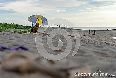 BADUNG,BALI/INDONESIA-APRIL 02 2019: Old man sits on the sand and enjoy sunbathing Editorial Stock Photo