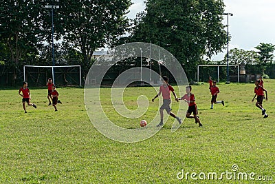 BADUNG,BALI/INDONESIA-APRIL 05 2019: Elementary student play football or soccer on the field with red jersey Editorial Stock Photo