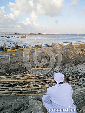 BADUNG/BALI-MAY 11 2018: a Hindu priest was bringing mobile phone and looking at the construction at the international airport Editorial Stock Photo