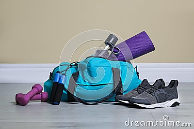 Bag with different sports equipment on wooden floor indoors Stock Photo