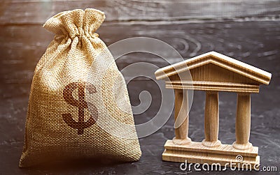 A bag with dollar money and a bank or government building. Deposits, investment in the budget. Grants and subsidies. Payment of Stock Photo