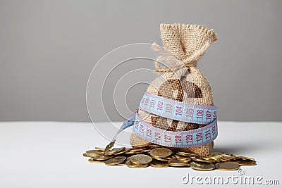 Bag with money and measuring tape on gold coins. Lack of money, poverty and savings Stock Photo