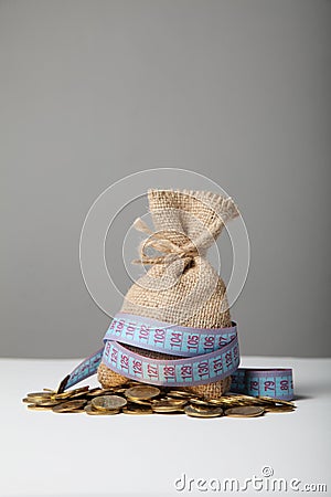 Bag with money and measuring tape on gold coins. Lack of money, poverty and savings Stock Photo