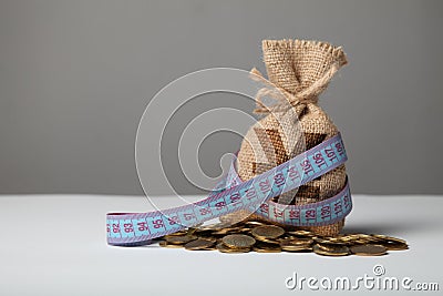 Bag with money and measuring tape on gold coins. Lack of money, poverty and savings Stock Photo