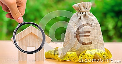 Bag with money and tape measure with a wooden house. Market crisis. The concept of a limited real estate budget. Low subsidies. Stock Photo