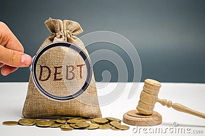 A bag of money and the word Debt and the hammer of the judge. Payment of taxes and of debt to the state. Concept of financial Stock Photo