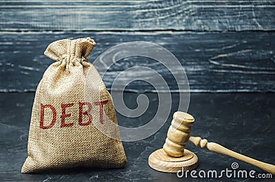 A bag of money and the word Debt and the hammer of the judge. Payment of taxes and of debt to the state. Concept of financial Stock Photo