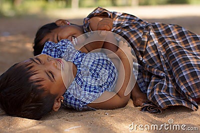 Bagan, Burma Myanmar - December 3, 2012. Close portrait of two small laughing Burmese girls lying on the sand Editorial Stock Photo
