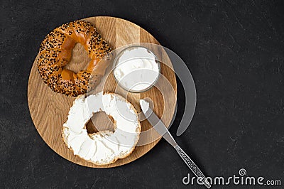 Bagel and cream cheese as a concept for breakfast. Wooden tray, black background Stock Photo