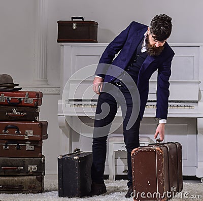 Baggage delivery concept. Man, traveller with beard and mustache with luggage, luxury white interior background. Macho Stock Photo