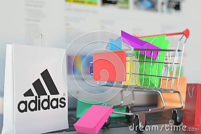 Bag with Adidas logo and shopping cart on a laptop keyboard. Editorial online shopping related 3D rendering Editorial Stock Photo