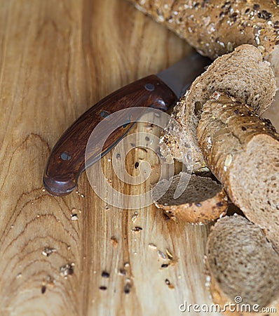 Baguette rye bread sprinkled with various seeds on a wooden board Stock Photo