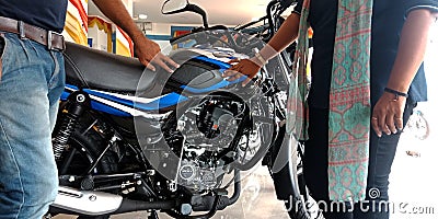 Bajaj automobile staff hand touching bike petrol tank at showroom in India Editorial Stock Photo