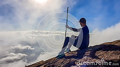 Bajawa - A man sitting on the side of a volcano, surrounded by clouds Stock Photo