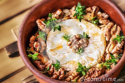 Baked brie cheese with honey, walnuts and thyme Stock Photo