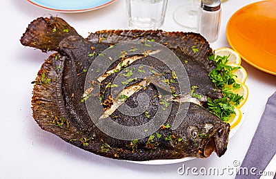 Baked brill fish with lemon and greens Stock Photo