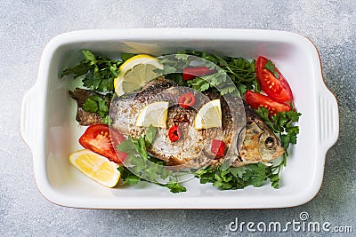 Baked carp fish with vegetables and spices in a baking tray Stock Photo