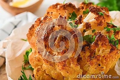 Baked cauliflower. Oven or whole baked cauliflower spices and herbs server on wooden rustic board on old white wooden background t Stock Photo