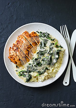 Baked chicken breast, mashed potatoes with creamy spinach on dark background, top view Stock Photo