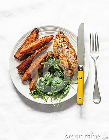 Baked chicken breast with sweet potatoes and spinach on a light background, top view. Balanced healthy lunch Stock Photo