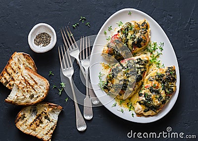 Baked chicken breast with tomatoes, spinach and mozzarella - delicious diet lunch in mediterranean style on a dark background Stock Photo