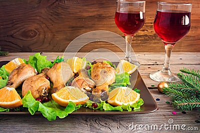 Baked chicken legs on a plate with greens, oranges and cranberri Stock Photo