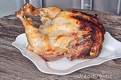 Baked chicken in a plate on a wooden table. Delicious chicken with a Golden crust. Stock Photo