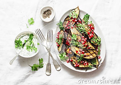 Baked eggplant with feta, greek yogurt, cilantro sauce and pomegranate seeds on light background, top view. Delicious snack, tapas Stock Photo