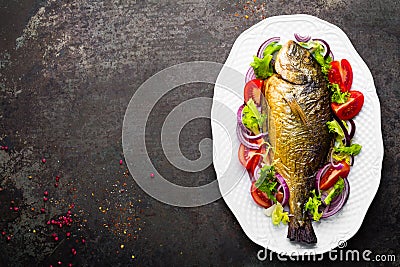 Baked fish dorado. Dorado fish oven baked and fresh vegetable salad on plate. Sea bream or dorada fish grilled and vegetable salad Stock Photo