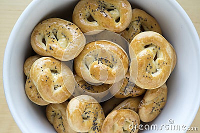 Baked fresh pretzels on white bowl on table, heart and twisted knot shapes, covered with poppy seeds salt and caraway seeds Stock Photo