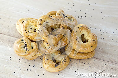 Baked fresh pretzels on wooden table, heart and twisted knot shapes, covered with poppy seeds salt and caraway seeds Stock Photo