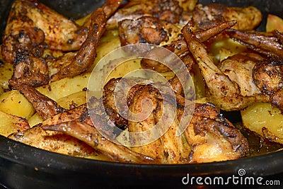 Baked fried potatoes with delicious fried chicken wings with golden crust served with sauces in black bowl on wooden table Stock Photo