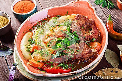 Baked meat with grilled vegetables, potatoes, greens in plate on wooden background. Stock Photo