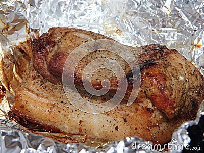 Baked piece of pork meat on aluminum foil, the process of cooking meat dishes in the oven. Stock Photo