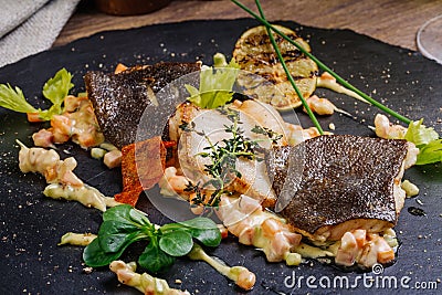 Baked plaice fillet with vegetables and sauce close-up on a bla Stock Photo