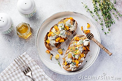 Baked pumpkin sandwich with dorblu cheese with blue mold, honey and thyme on a concrete old light background. Stock Photo