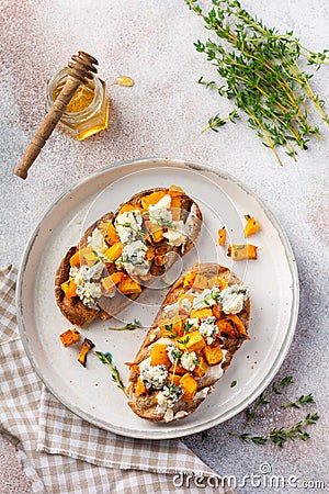 Baked pumpkin sandwich with dorblu cheese with blue mold honey and thyme on a concrete old light background. Top view Stock Photo
