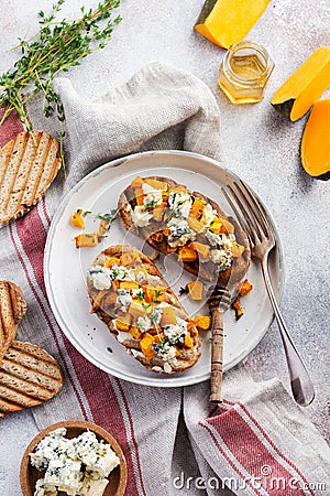 Baked pumpkin sandwich with dorblu cheese with blue mold, honey and thyme on a concrete old light background. Top view Stock Photo