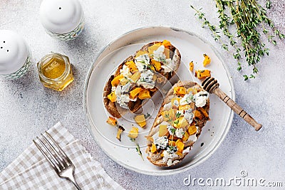 Baked pumpkin sandwich with dorblu cheese with blue mold, honey and thyme on a concrete old light background. Top view Stock Photo